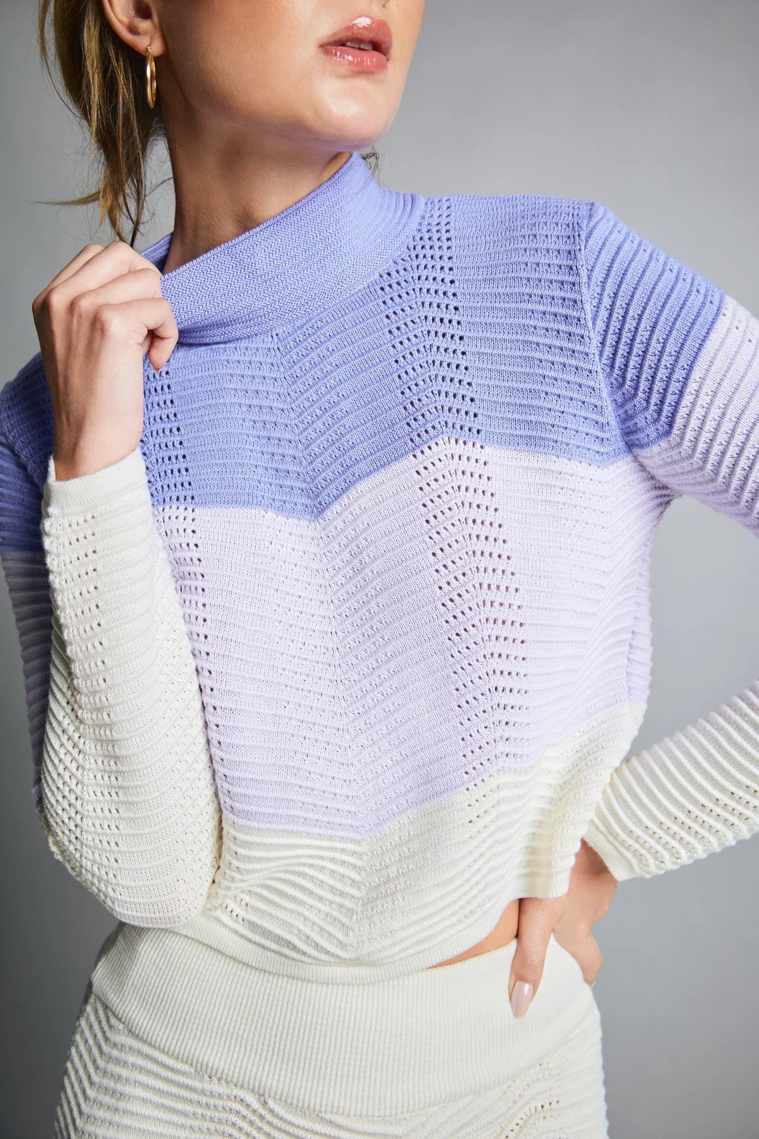 Mujer con suéter tejido de punto en tonos lila, lavanda y blanco, ropa de moda femenina.